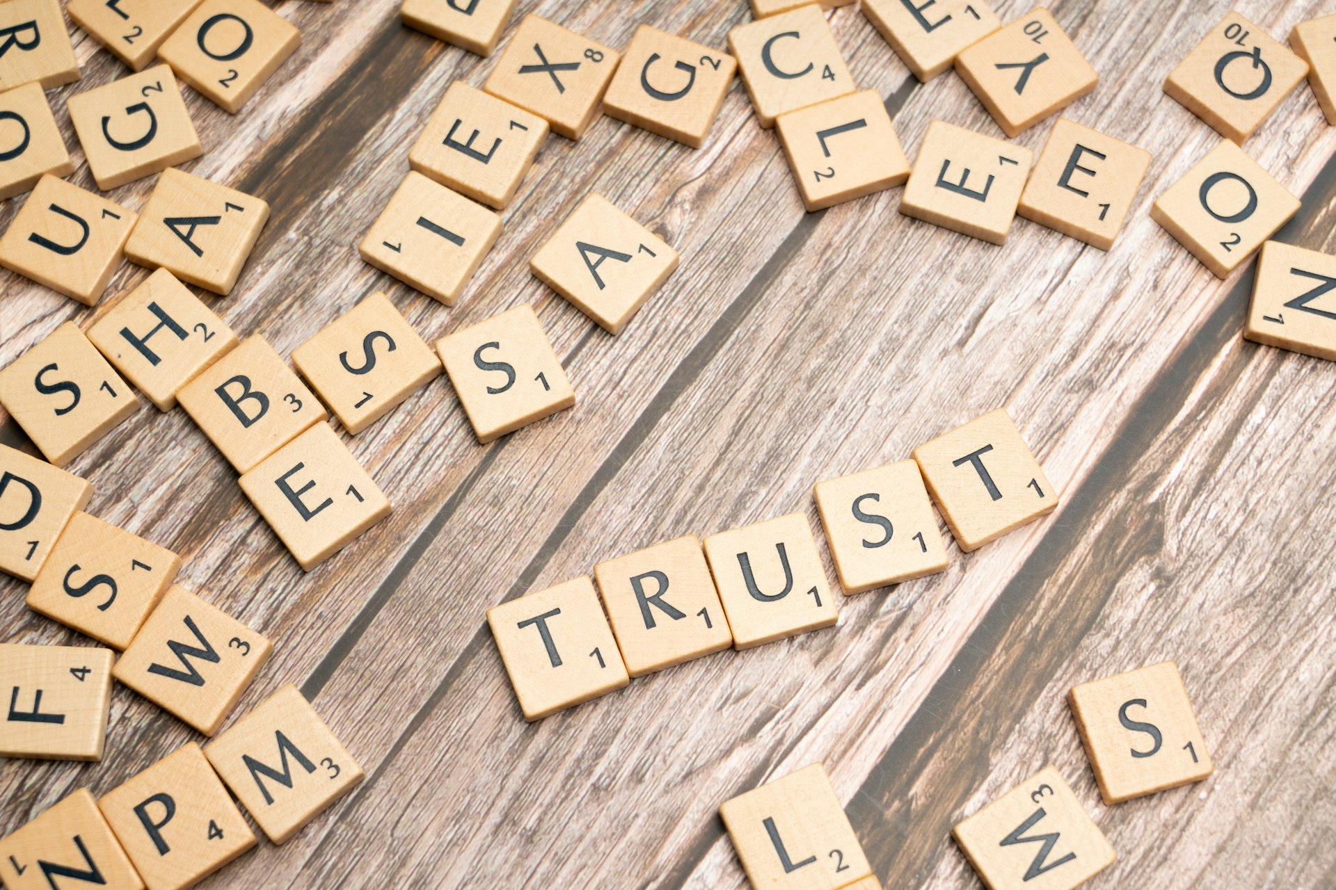 scrabble tiles spelling the word trust on a wooden surface
